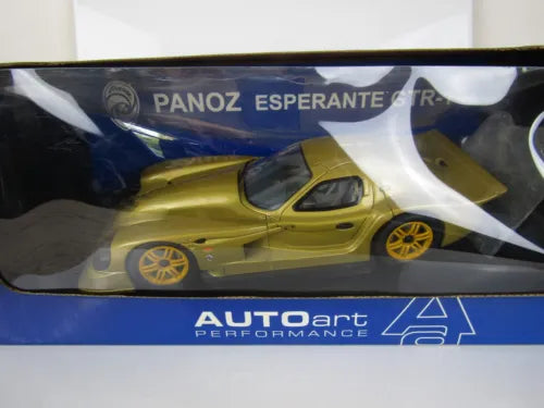 Gold diecast sports car model in display case, black rear wing and wheels visible