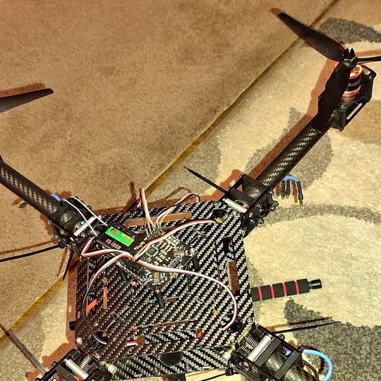 Carbon fiber quadcopter drone with exposed circuit board and propellers
