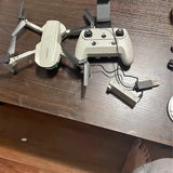 White quadcopter drone with remote controller and charging cable