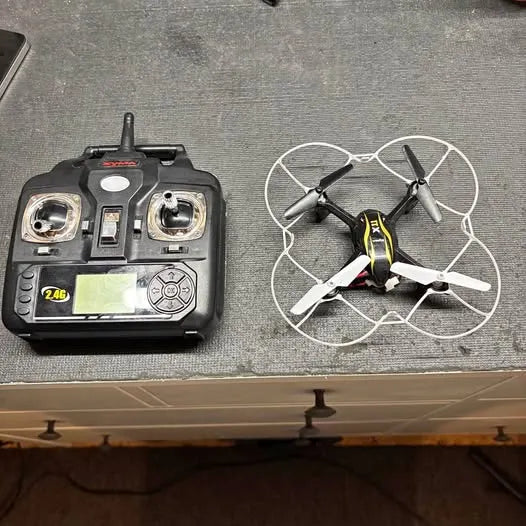 Syma X11 quadcopter drone with black remote controller, four propellers
