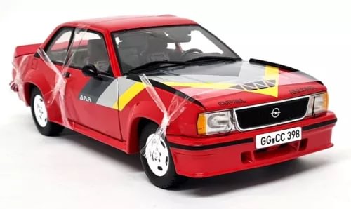 Red diecast model car, front three-quarter view with black grille and headlights
