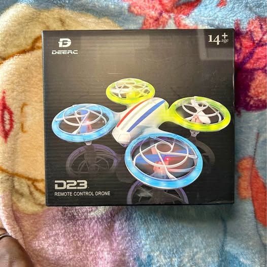 D23 remote control drone in retail box with four propellers, blue and yellow rings.