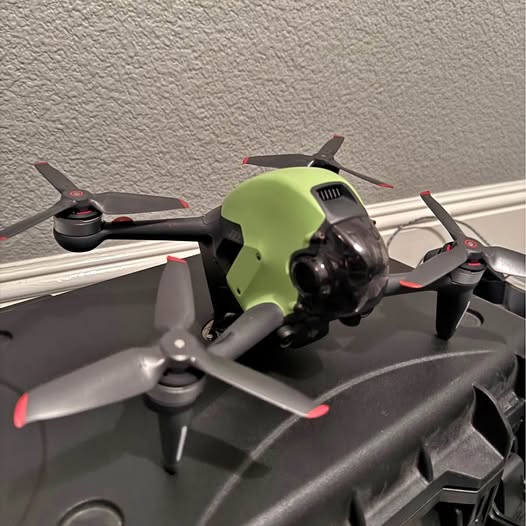 FPV drone with green camera housing and four black propellers