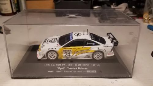 White diecast touring car model with blue and yellow racing decals, 1:43 scale