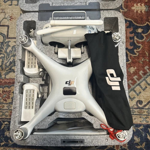 White quadcopter drone with camera, landing gear, and black prop guards