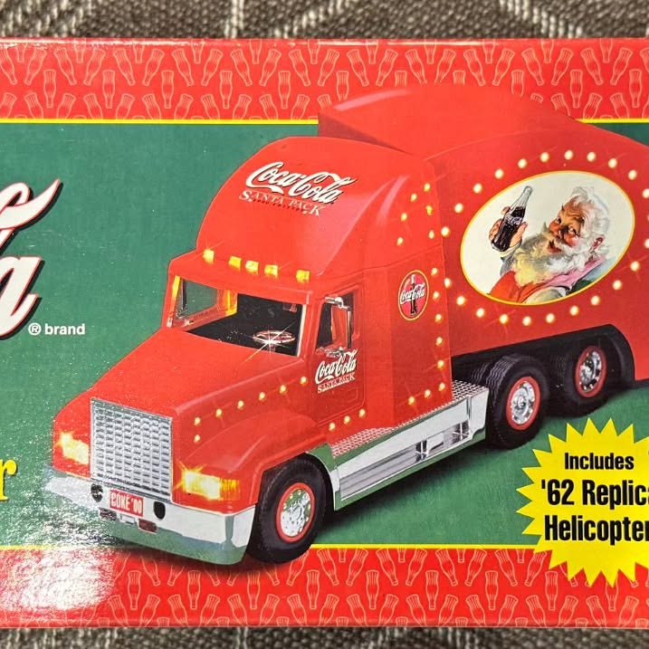Red Coca-Cola diecast delivery truck with front grille and Santa-themed cab