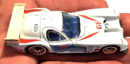 White Hot Wheels diecast race car with red stripes and blue windshield, front 3/4 view