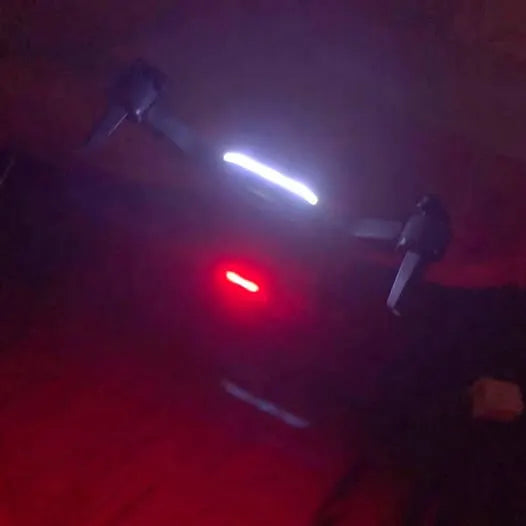 Compact quadcopter drone with red and white LED lights, dark body