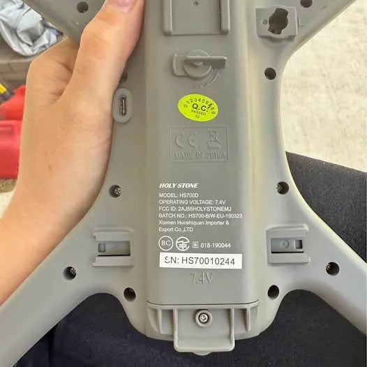 Gray drone underside with label panel, screws, and battery housing ports