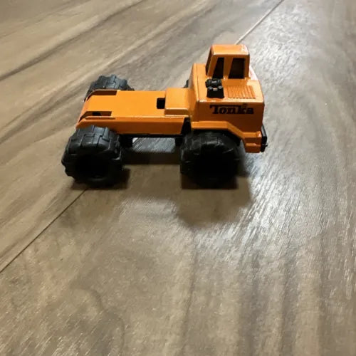 Orange metal diecast mini truck tractor with black wheels, side view
