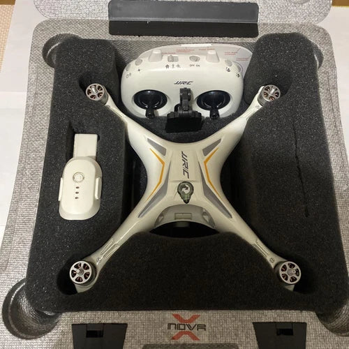White quadcopter drone with four propellers and gray remote controller in case