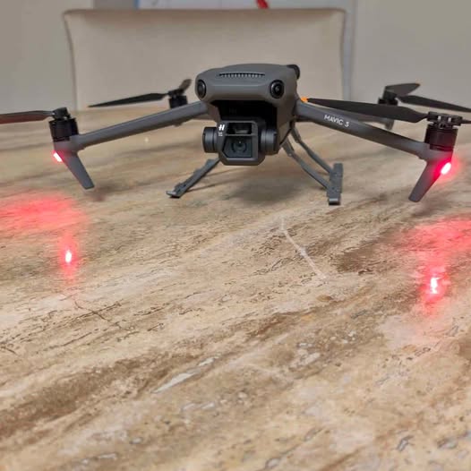 Foldable quadcopter drone, front camera module and four propeller arms visible.
