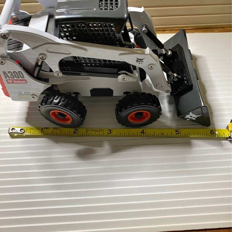 Gray diecast skid-steer loader model with front bucket and black wheels