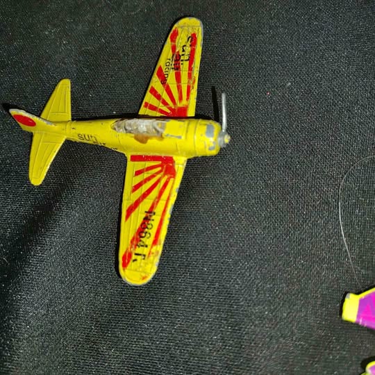 Diecast military jet airplane, yellow with red markings and propeller nose