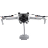 Plastic desktop drone stand with center pole and gray base holding a drone