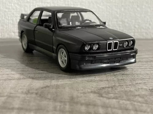 Matte black die-cast car model, front three-quarter view with detailed grille and lights