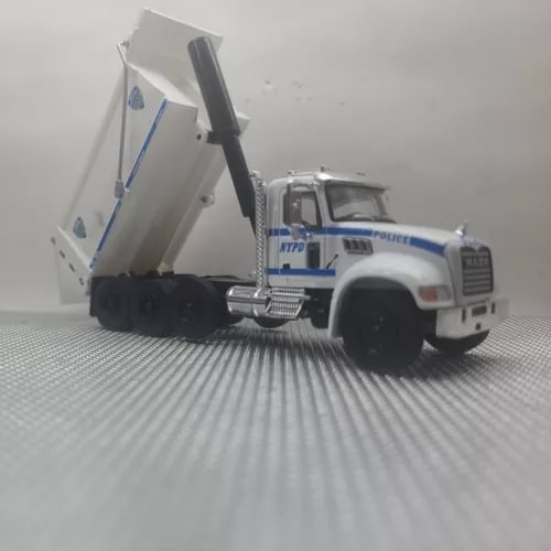 White and blue diecast dump truck with open bed, front three-quarter view