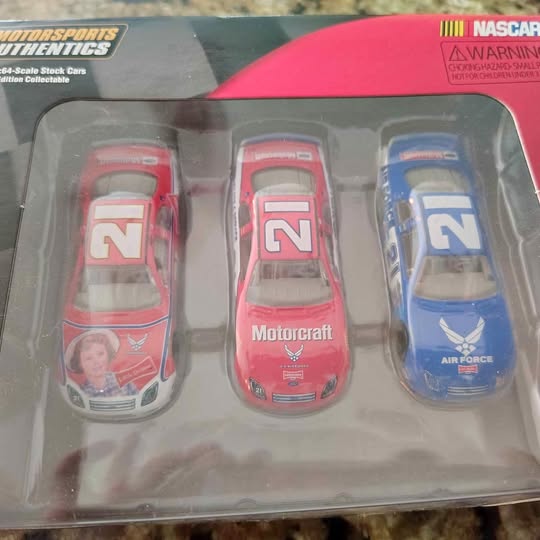 Three diecast race cars with large 'N' numbers, two red and one blue, in blister