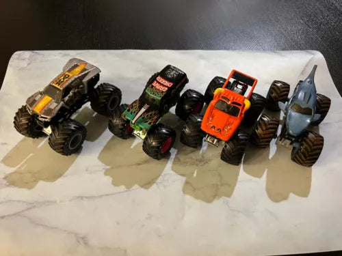 Diecast monster truck set with multiple colorful trucks and large rugged wheels