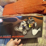 Altered diecast model car in retail box, graphic artwork of three-wheeled vehicle