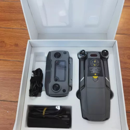 Gray drone with controller, cables and accessories in open box insert