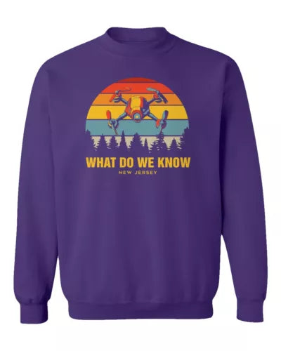 Unisex crewneck sweatshirt in purple with retro drone graphic and “What Do We Know” text