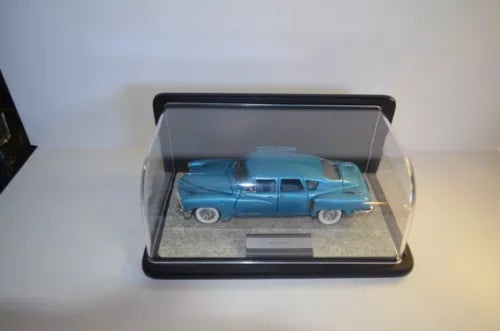 Light blue 1:24 diecast car in clear display case, pedestal base