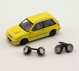 Yellow 1:64 diecast car with black wheels and two sets of spare rims