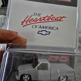 Diecast pickup truck model in a clear display window, light gray cab and bed