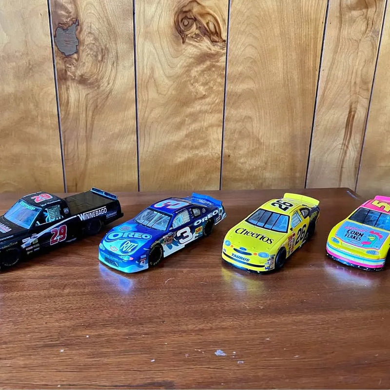 Four diecast race cars, blue and yellow with racing numbers and sponsor decals
