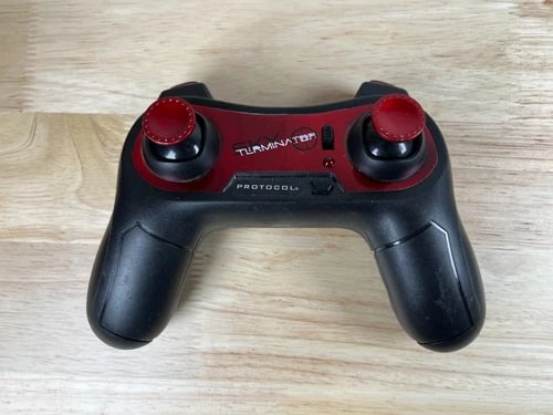 Drone remote controller, black with red thumbsticks and buttons, center logo details