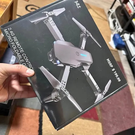 Foldable drone box displaying drone with four propellers and remote control icon
