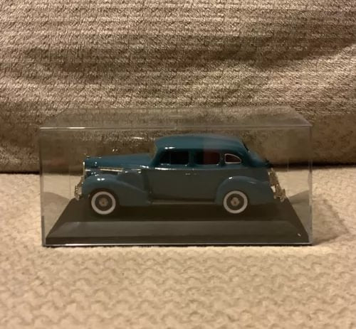 Dark blue diecast sedan model in clear display case, front three-quarter view