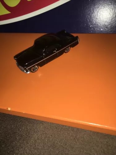 Black diecast model car in side view, detailed wheels and chrome trim