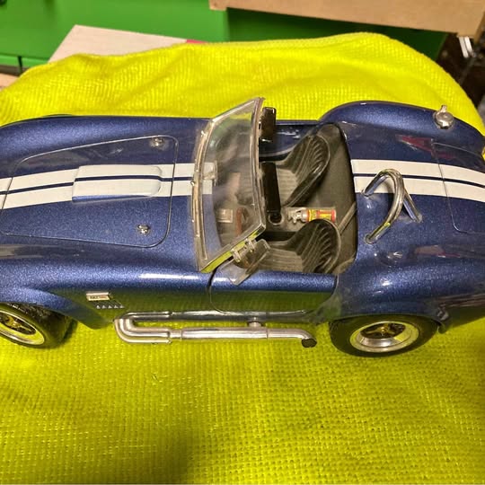 Blue Shelby Cobra diecast model car with open front hood and chrome details