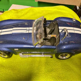 Blue Shelby Cobra diecast model car with open front hood and chrome details