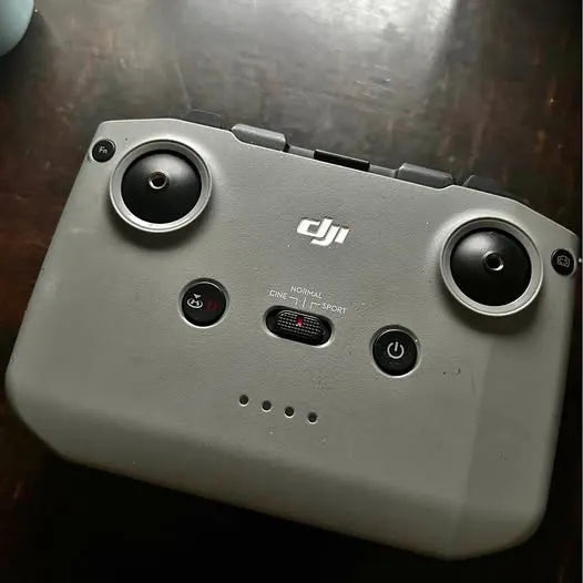 DJI drone controller in gray with two thumb sticks, buttons, and DJI logo