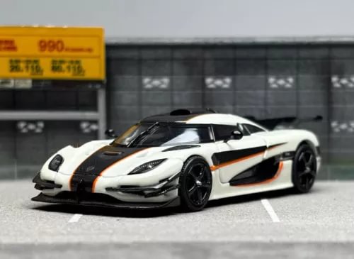 Diecast sports race car model, white with orange stripes and black hood, front 3/4 view
