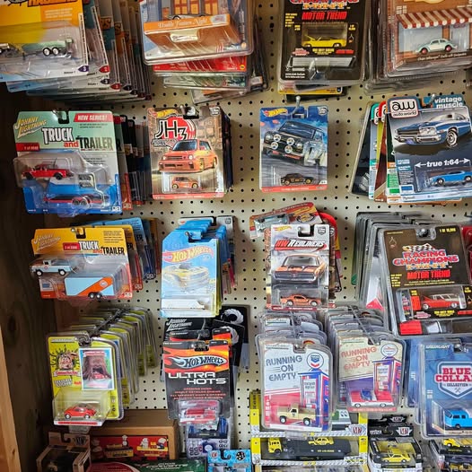 Diecast car and truck model display with multiple boxed vehicles on a pegboard