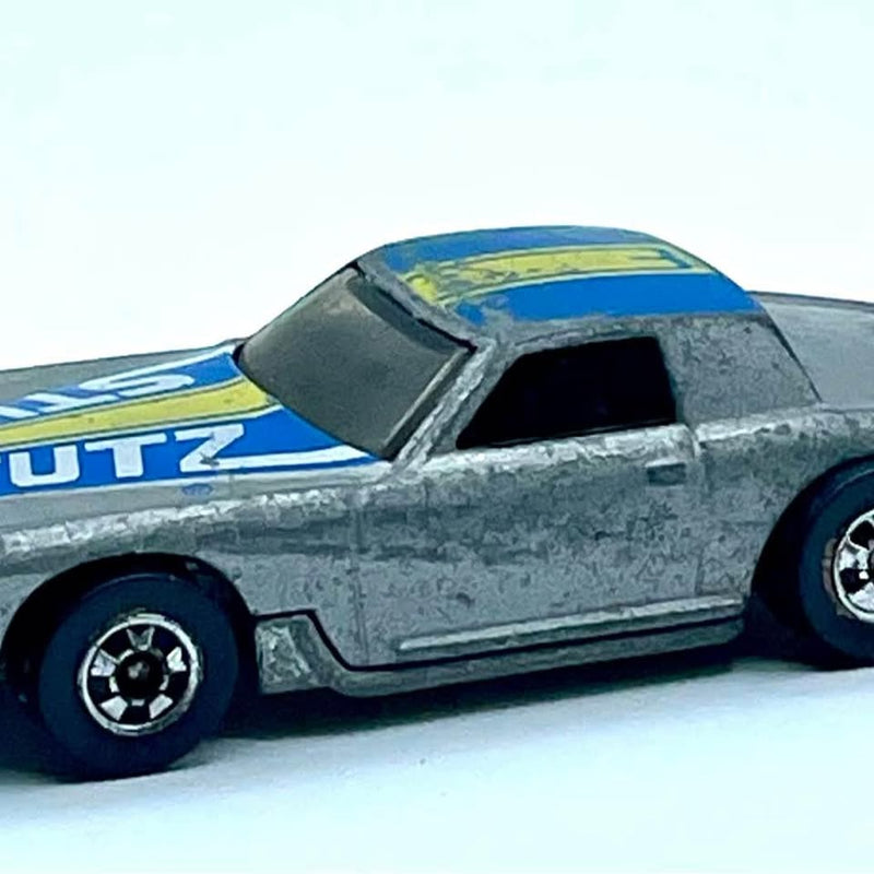Vintage diecast car with silver body, blue windshield, black wheels, side view