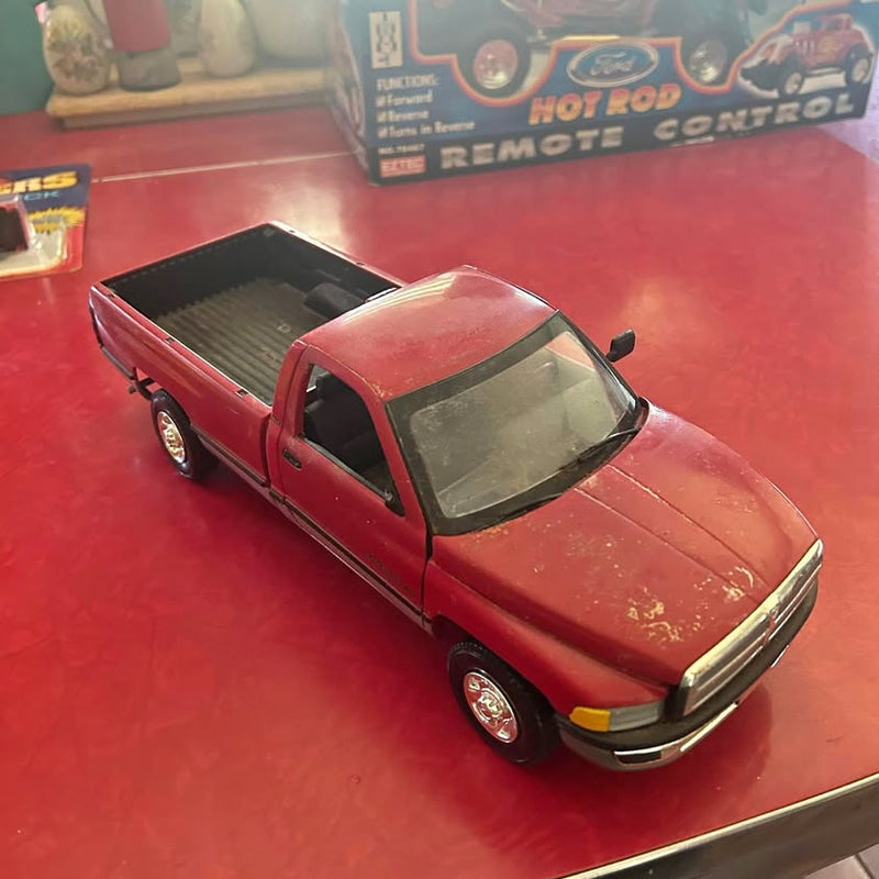 Red diecast pickup truck model with black wheels and hood stripe, front 3/4 view