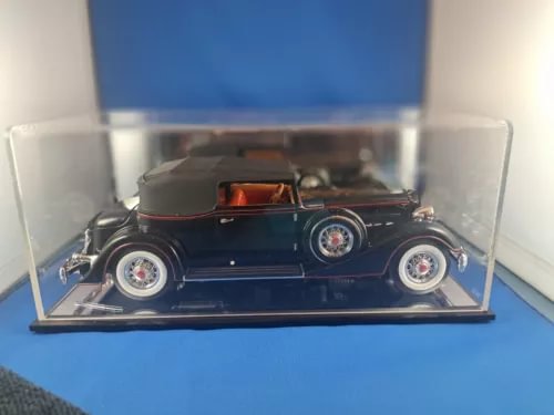 Diecast model car in display case, dark blue open-top convertible with tan interior