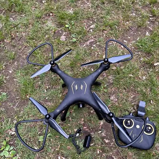 Drone quadcopter with four propellers and dark body, paired with handheld remote