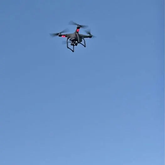Quadcopter drone with four rotors and red accents, hovering