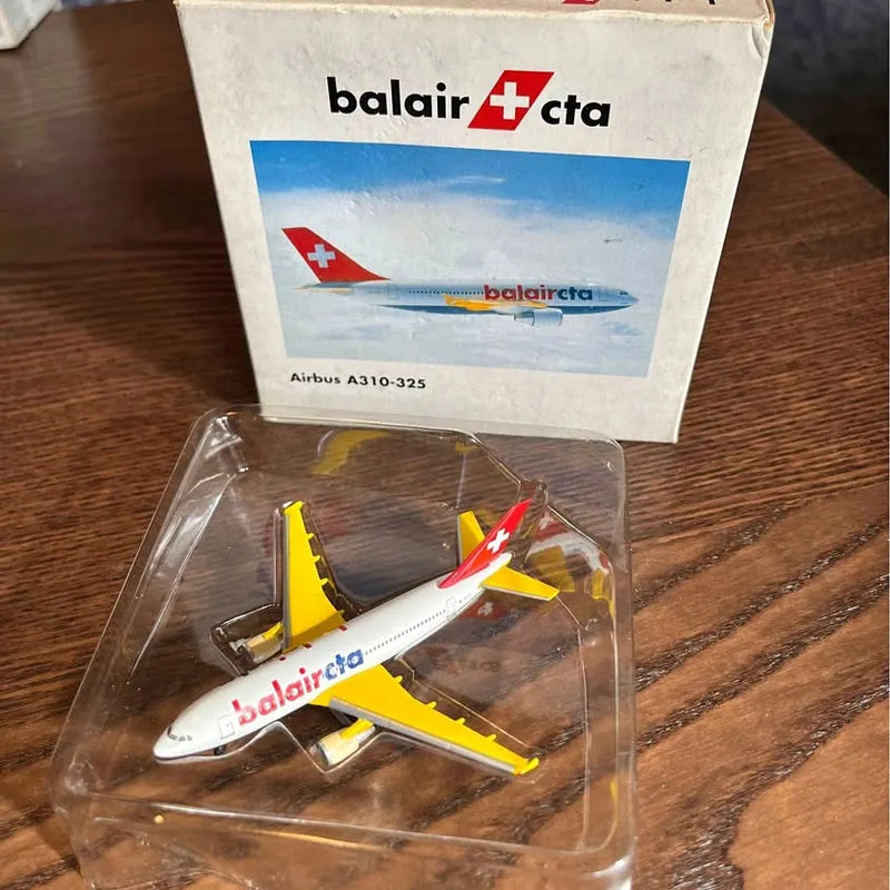 Diecast airplane model with white fuselage and yellow wings, red cross tail, in clear box.