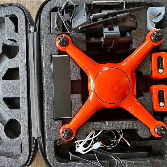 Orange quadcopter drone in open hard case with controller and batteries