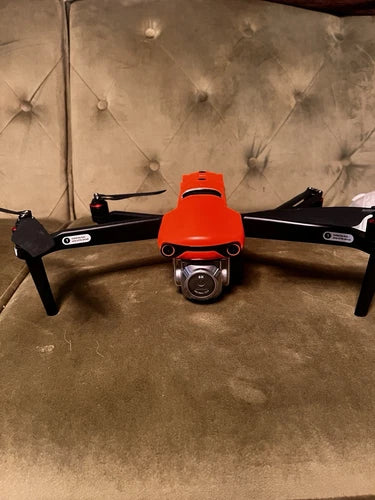 Orange quadcopter drone with front camera gimbal and four prop arms