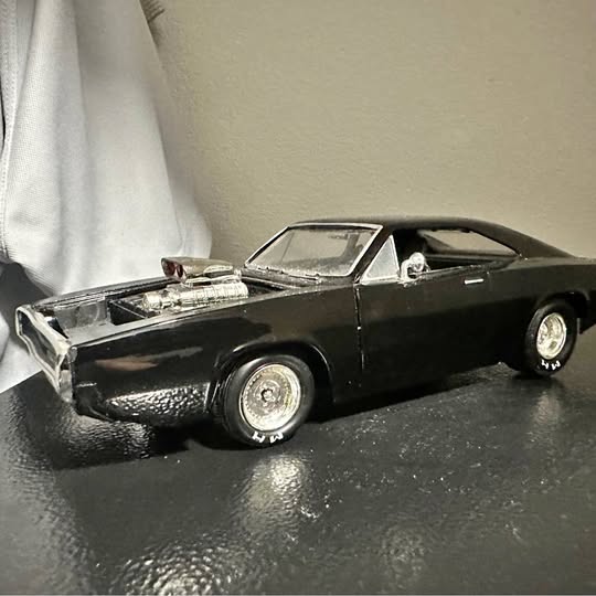 Black diecast muscle car with chrome grille, front 3/4 view