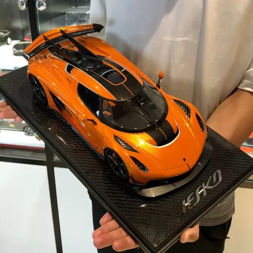 Orange and black sports car diecast model on textured display base, front 3/4 view