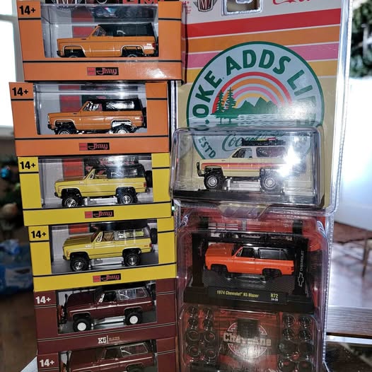 Diecast toy truck in blister packaging with orange vehicle and dark base